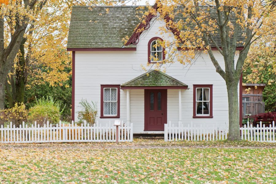 White wooden holiday bungalow with a porch and picket fence